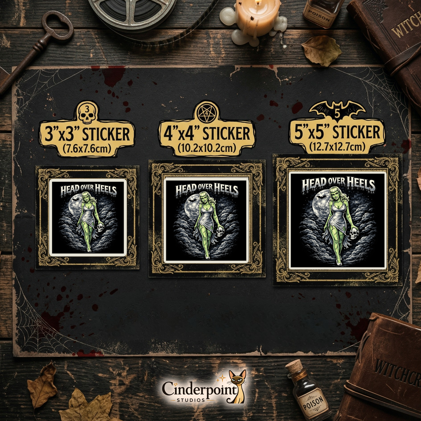 A dark wood tabletop featuring three "Head Over Heels" stickers in 3-inch, 4-inch, and 5-inch sizes. Styled with a "Witchcraft" grimoire, poison bottles, a candle, and a brass skeleton key.