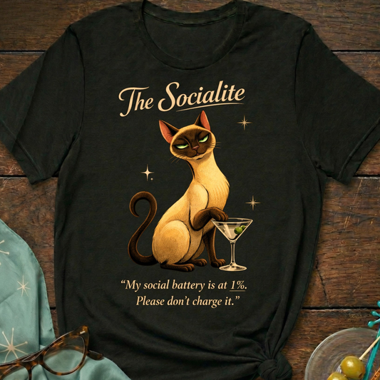 The Socialite Book of Lyle t-shirt design featuring Lyle, a sleek Siamese cat beside a martini glass with the quote “My social battery is at 1%. Please don’t charge it.”