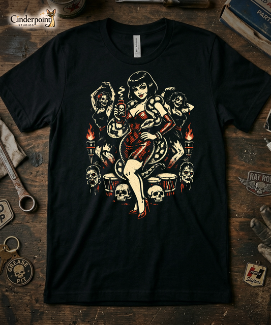 The Voodoo Vixen t-shirt laid flat on a weathered wooden workbench. Surrounded by a vintage 'Hurst Shifters' patch, a 'Rat Rod' wing emblem, an old wrench, and a 'Grease Pit' skull keychain. The high-contrast red and cream art pops against the black fabric and dark wood. Cinderpoint Studios Siamese cat logo is placed in the top-left corner.