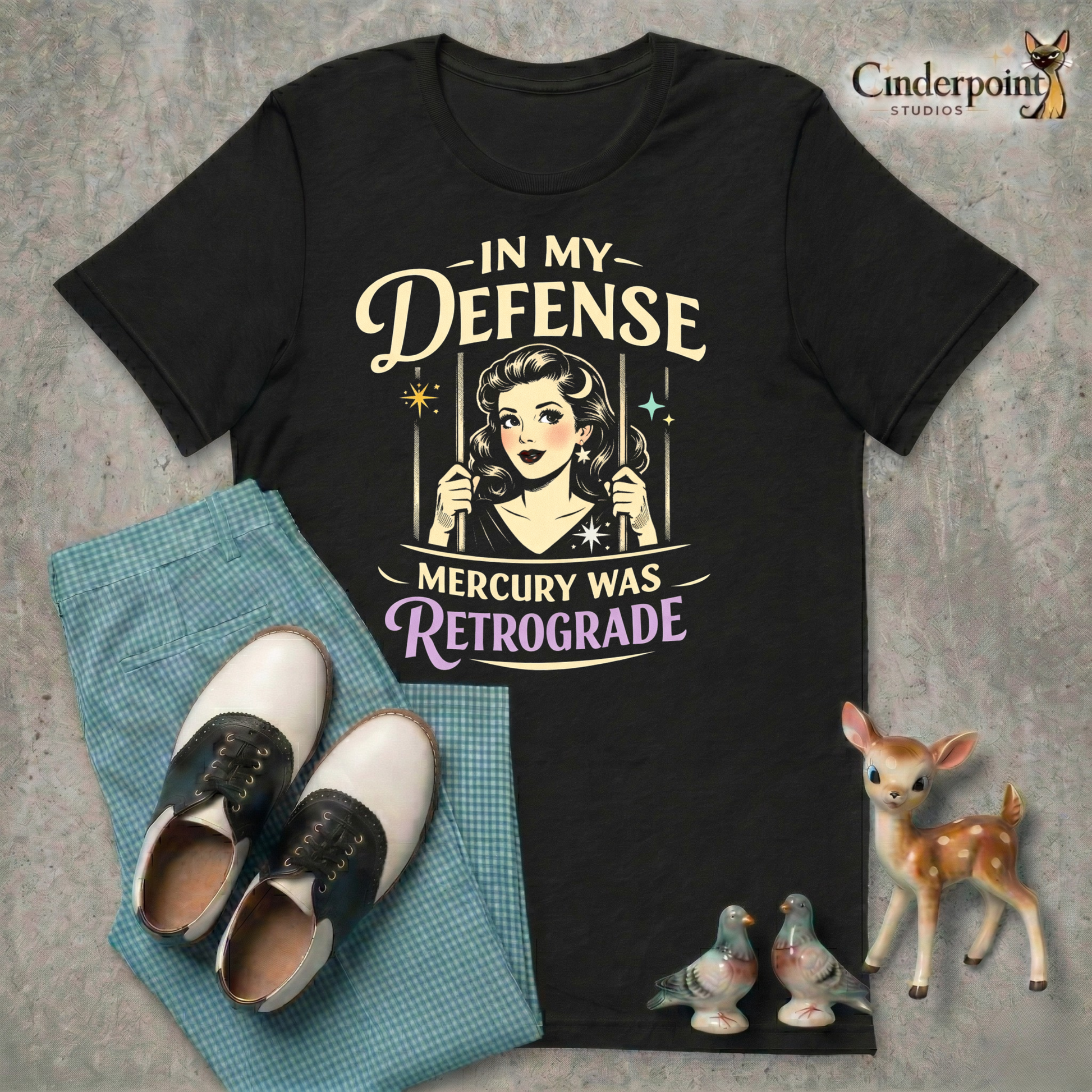 Black retro graphic t-shirt featuring a vintage-inspired woman behind bars with the phrase In My Defense Mercury Was Retrograde in cream and lavender lettering.