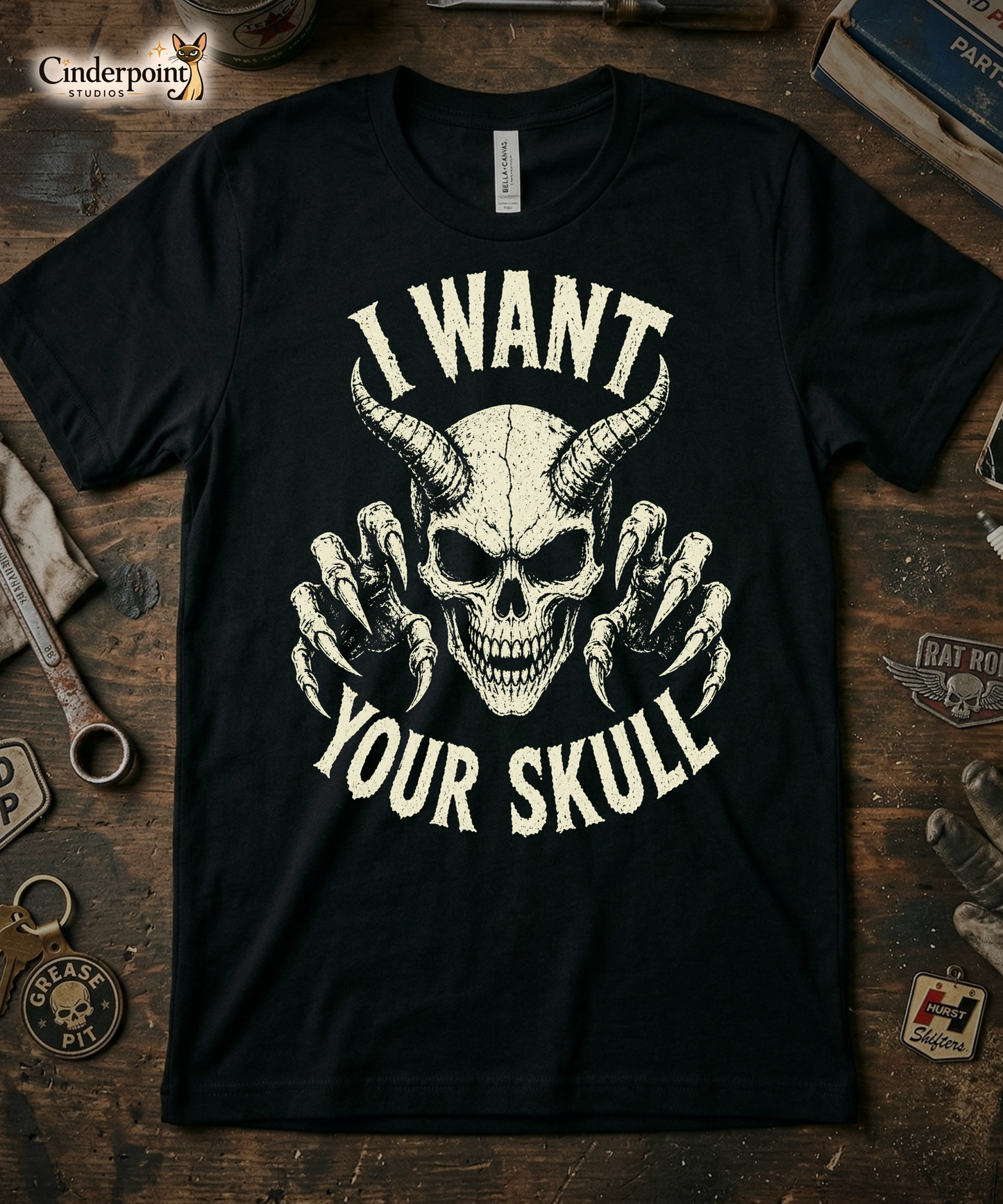 A retro-style graphic on a black t-shirt featuring a detailed horned demon skull with sharp claws and "I WANT YOUR SKULL" in distressed punk-rock lettering.
