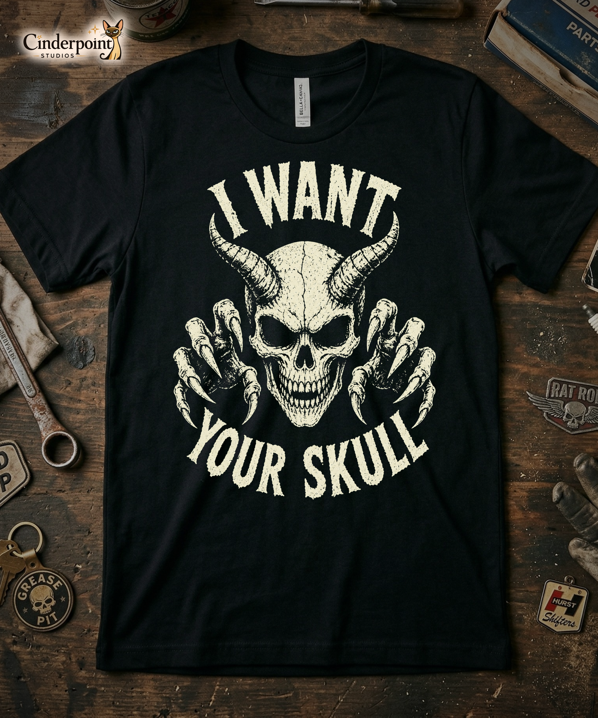 A retro-style graphic on a black t-shirt featuring a detailed horned demon skull with sharp claws and "I WANT YOUR SKULL" in distressed punk-rock lettering.