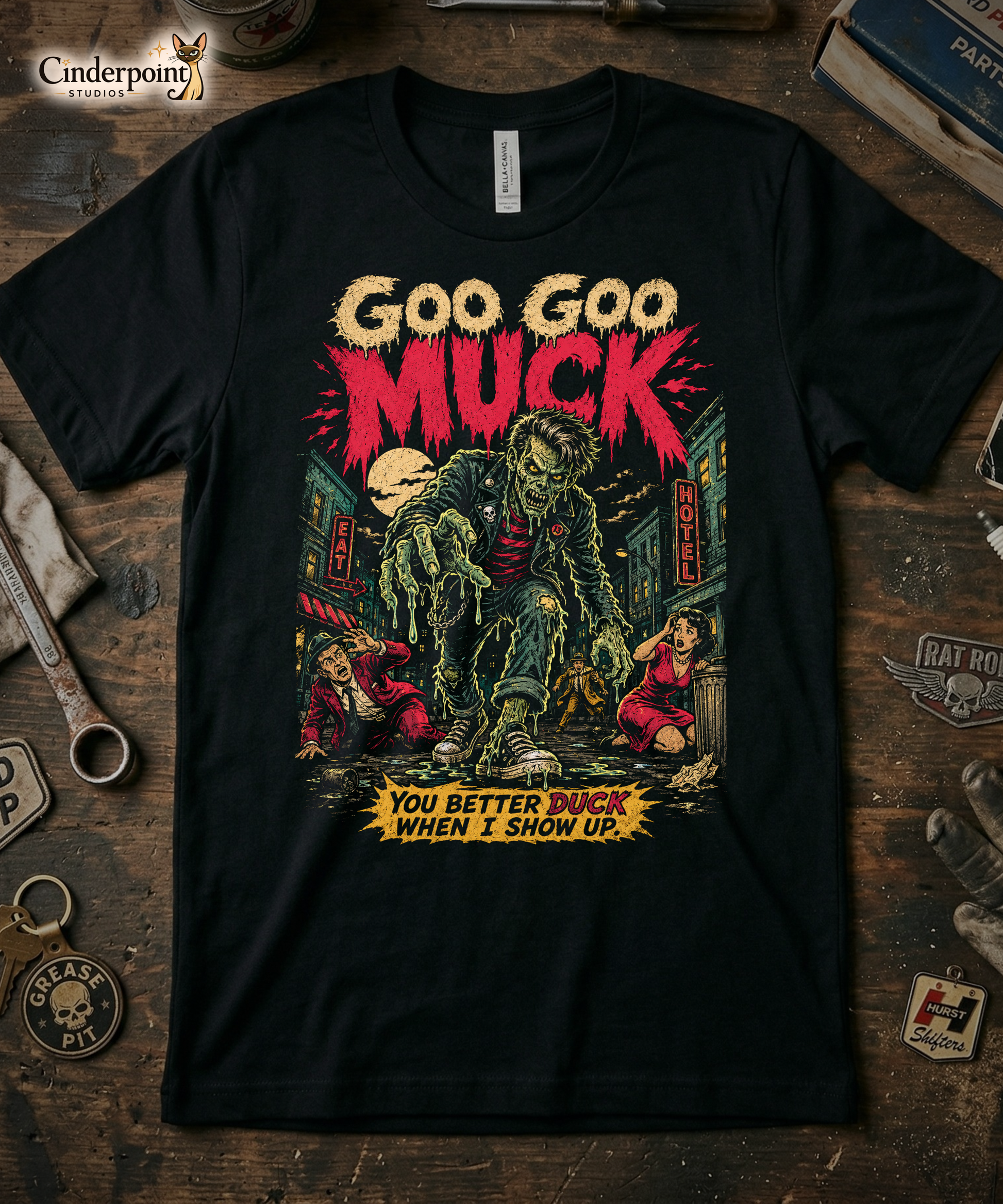 A retro-style graphic on a black t-shirt featuring a teenage monster with a pompadour, wearing a red and black striped shirt and a black leather jacket, with "GOO GOO MUCK" in distressed lettering.