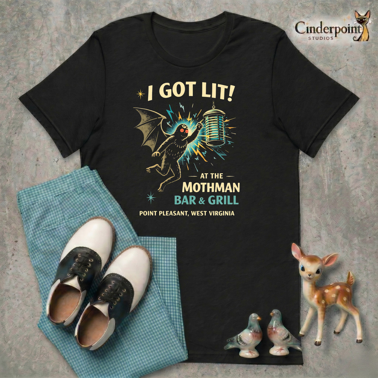 Black retro graphic t-shirt featuring Mothman flying into a glowing bug light with the phrase I Got Lit at the Mothman Bar and Grill, Point Pleasant, West Virginia.