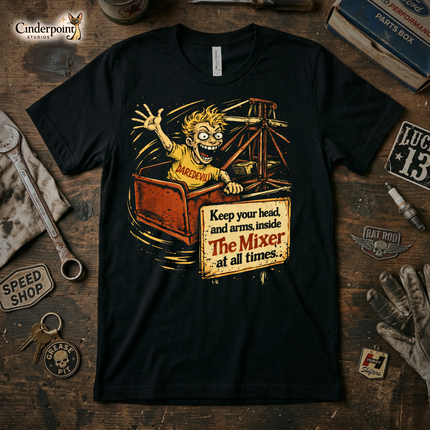 A black t-shirt featuring a distressed graphic of a manic-looking boy in a "DAREDEVIL" shirt on a carnival ride called "The Mixer," with a sign saying "Keep your head and arms inside."