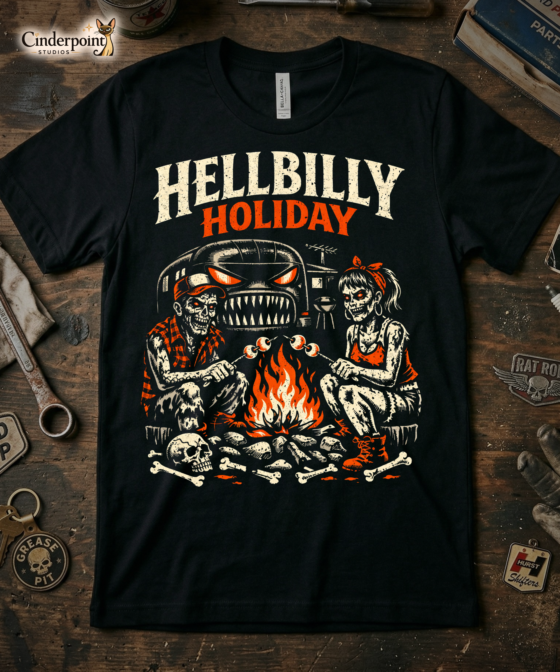 A high-contrast lowbrow illustration titled 'Hellbilly Holiday'. Two zombies—a man in a trucker hat and a woman with a red bandana—roast marshmallows over a campfire made of skulls and bones. A monster-faced airstream-style trailer with glowing eyes and sharp teeth looms in the background. Distressed cream and orange ink on a black background.