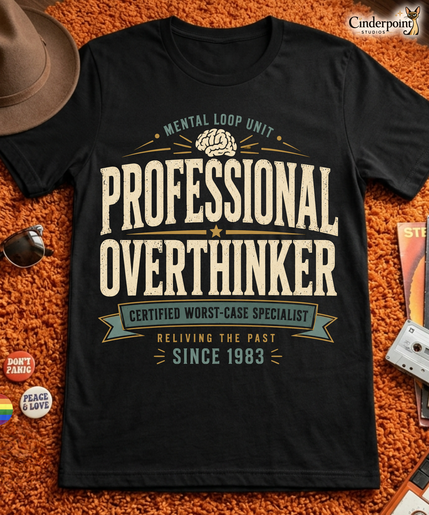 Black graphic tee featuring original Cinderpoint Studios artwork for Professional Overthinker, a retro badge-style design with bold vintage lettering, a brain graphic, and text including Mental Loop Unit, Certified Worst-Case Specialist, and Reliving the Past Since 1983.