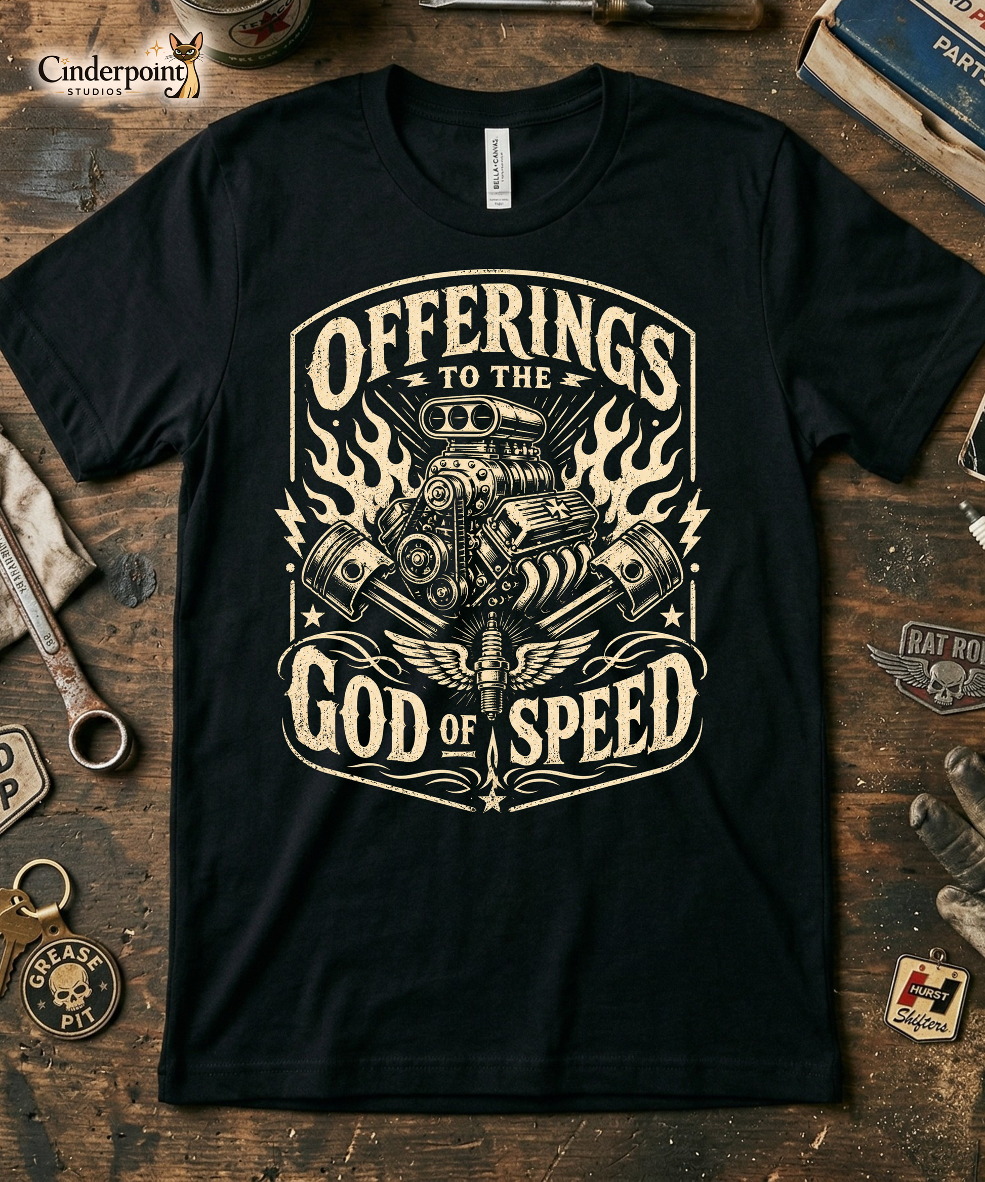 Black graphic tee featuring original Cinderpoint Studios artwork for Offerings to the God of Speed, a one-color retro gearhead design with a supercharged V8 engine, crossed pistons, winged spark plug, flames, lightning bolts, and vintage hot rod lettering.
