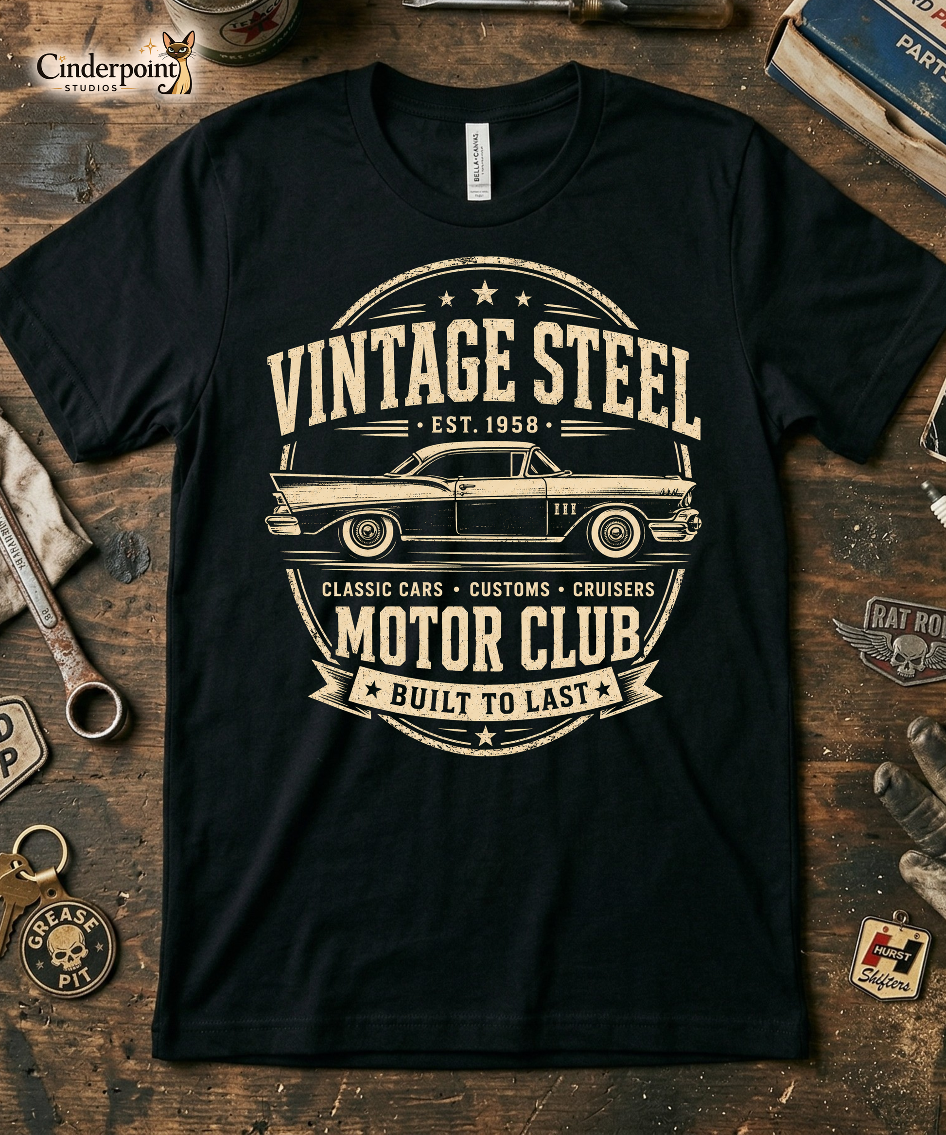 Workbench with a black graphic tee featuring original Cinderpoint Studios artwork for Vintage Steel Motor Club, a one-color classic car club design with a side-profile vintage car, bold lettering, stars, badge-style framing, Classic Cars Customs Cruisers text, and Built to Last banner.