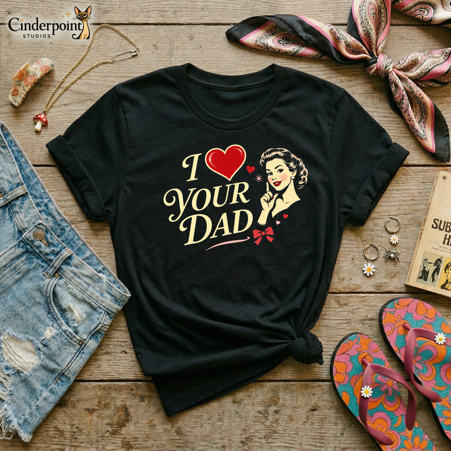 Black t-shirt with 'I ❤️ YOUR DAD' design on a wooden surface with accessories.