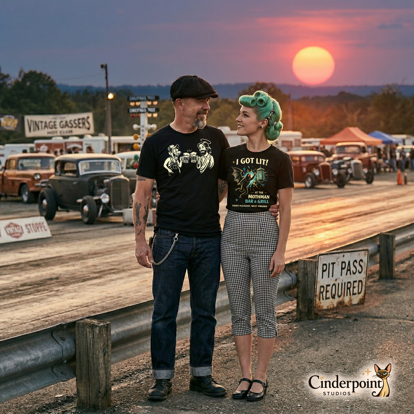 A rockabilly couple standing at a drag strip during sunset; the man wears the "Drinking With Jesus" tee while the woman stands next to him in her favorite subversive gear.