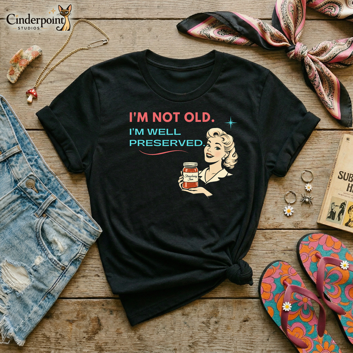 Black retro graphic t-shirt featuring a smiling vintage-inspired woman holding a jar of strawberry jam with the phrase I’m Not Old, I’m Well Preserved in coral and aqua lettering.