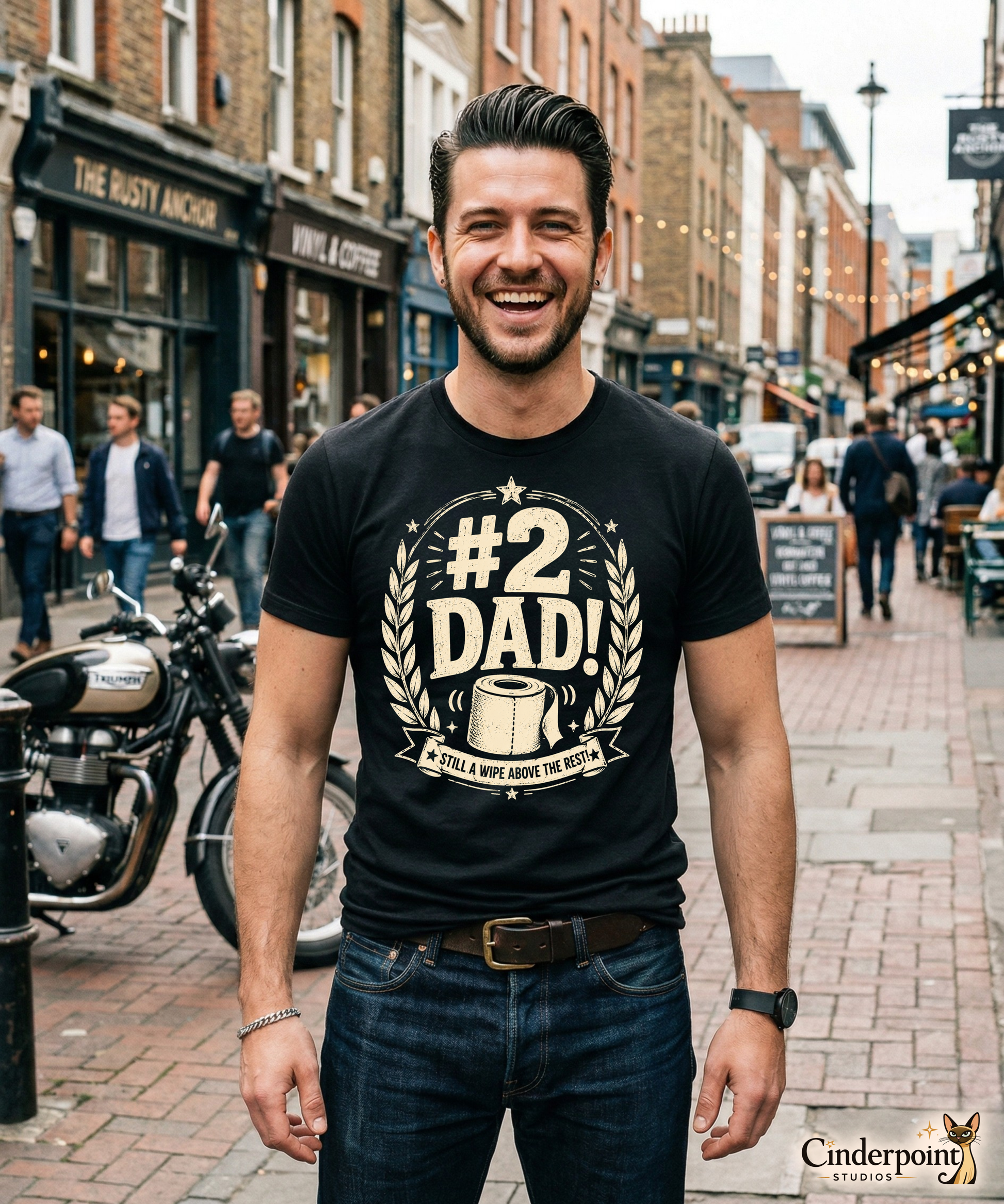 Man wearing a black graphic tee featuring original Cinderpoint Studios artwork for #2 Dad, a one-color funny dad design with bold retro lettering, laurel accents, stars, a toilet paper roll illustration, and the phrase Still a Wipe Above the Rest!
