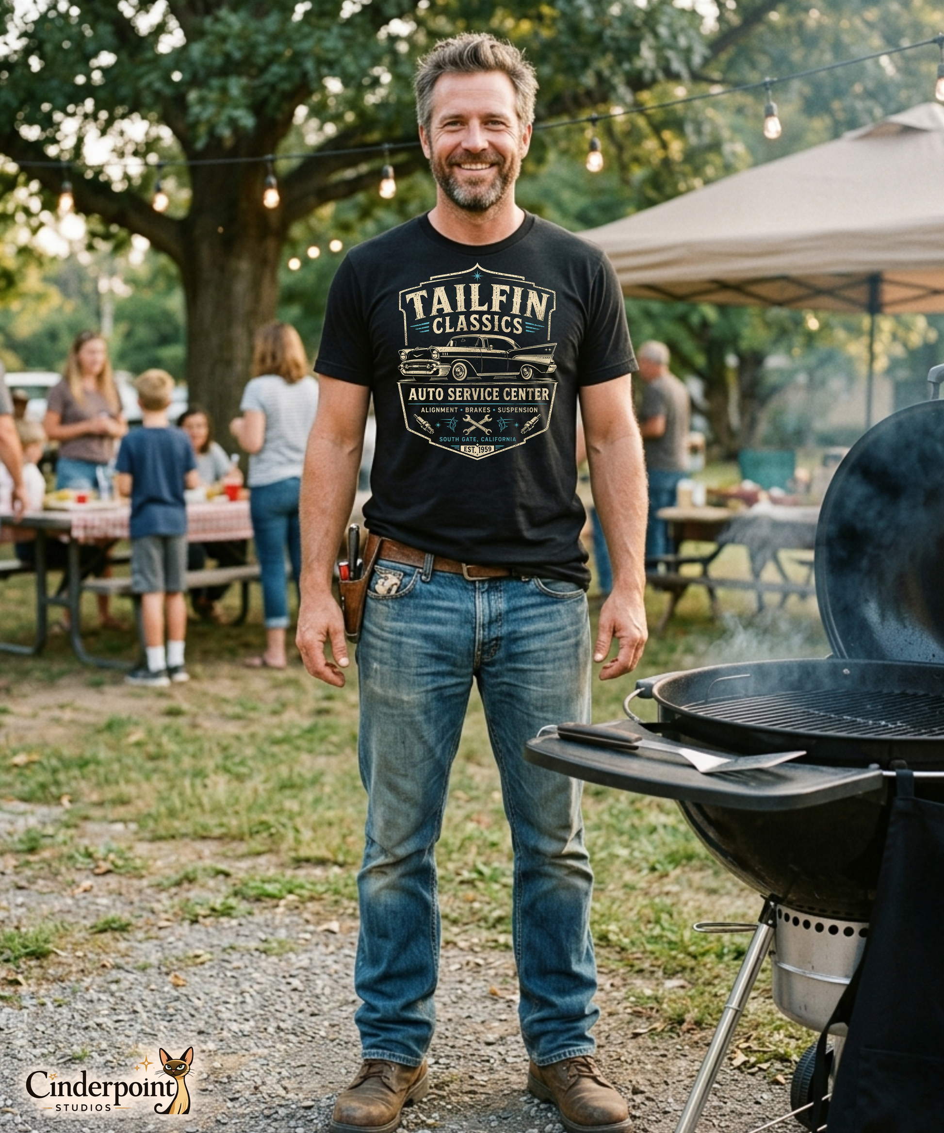 Man standing next to a barbecue grill at an outdoor event with 'Tailfin Classics' t-shirt.