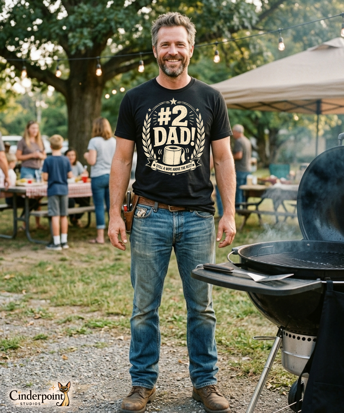 Man wearing a black graphic tee featuring original Cinderpoint Studios artwork for #2 Dad, a one-color funny dad design with bold retro lettering, laurel accents, stars, a toilet paper roll illustration, and the phrase Still a Wipe Above the Rest!
