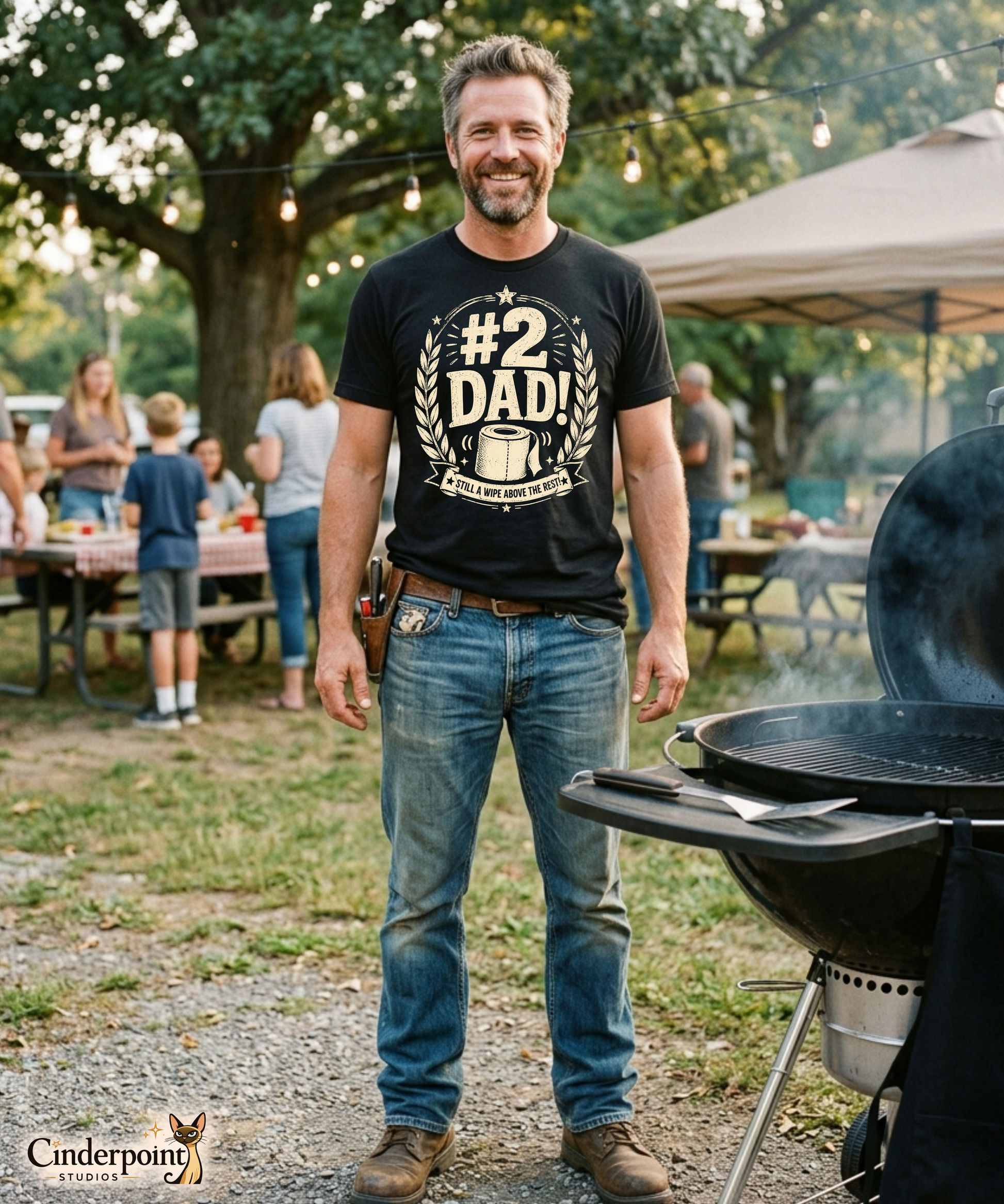 Man wearing a black graphic tee featuring original Cinderpoint Studios artwork for #2 Dad, a one-color funny dad design with bold retro lettering, laurel accents, stars, a toilet paper roll illustration, and the phrase Still a Wipe Above the Rest!