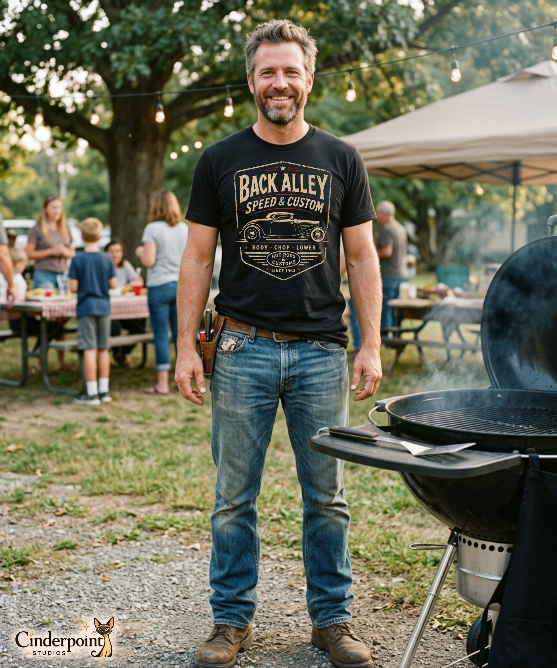 Man cooking on a grill wearing a black graphic tee featuring original Cinderpoint Studios artwork for Back Alley Speed & Custom, a retro hot rod garage design with a chopped custom car profile, bold distressed lettering, red accent details, Body Chop Lower text, and Hot Rods & Customs badge.