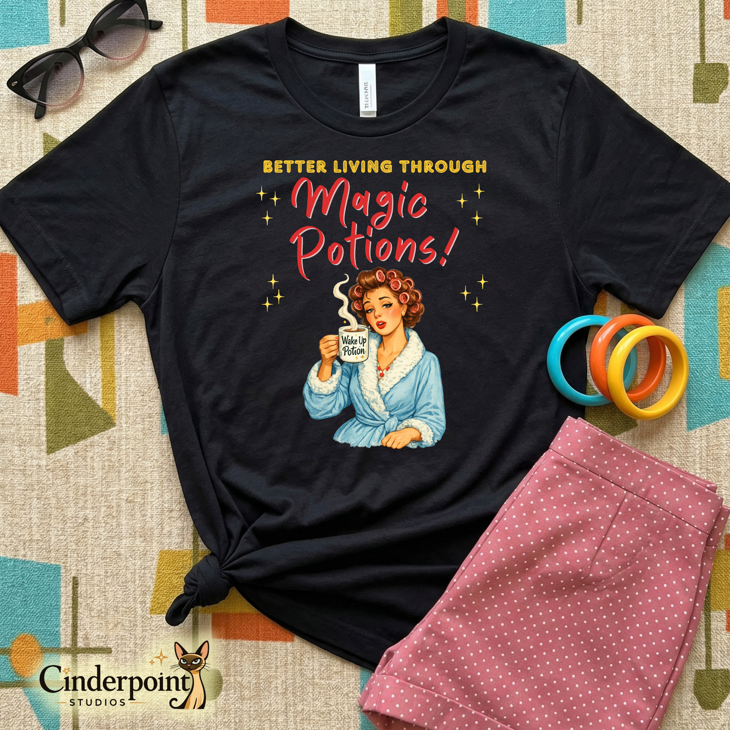 Retro watercolor illustration of a 1950s woman in a blue robe and hair curlers holding a steaming mug labeled "Wake Up Potion" on a black t-shirt.