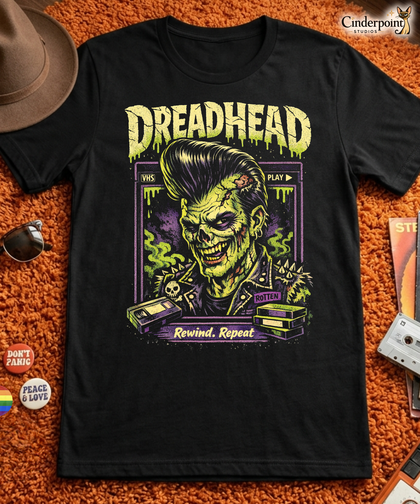 A retro 80s horror-style graphic on a black t-shirt featuring a zombie greaser with a pompadour and "Dreadhead" and "Rewind Repeat" in distressed VHS-style lettering.