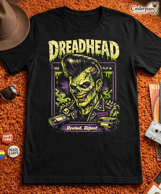 A retro 80s horror-style graphic on a black t-shirt featuring a zombie greaser with a pompadour and "Dreadhead" and "Rewind Repeat" in distressed VHS-style lettering.
