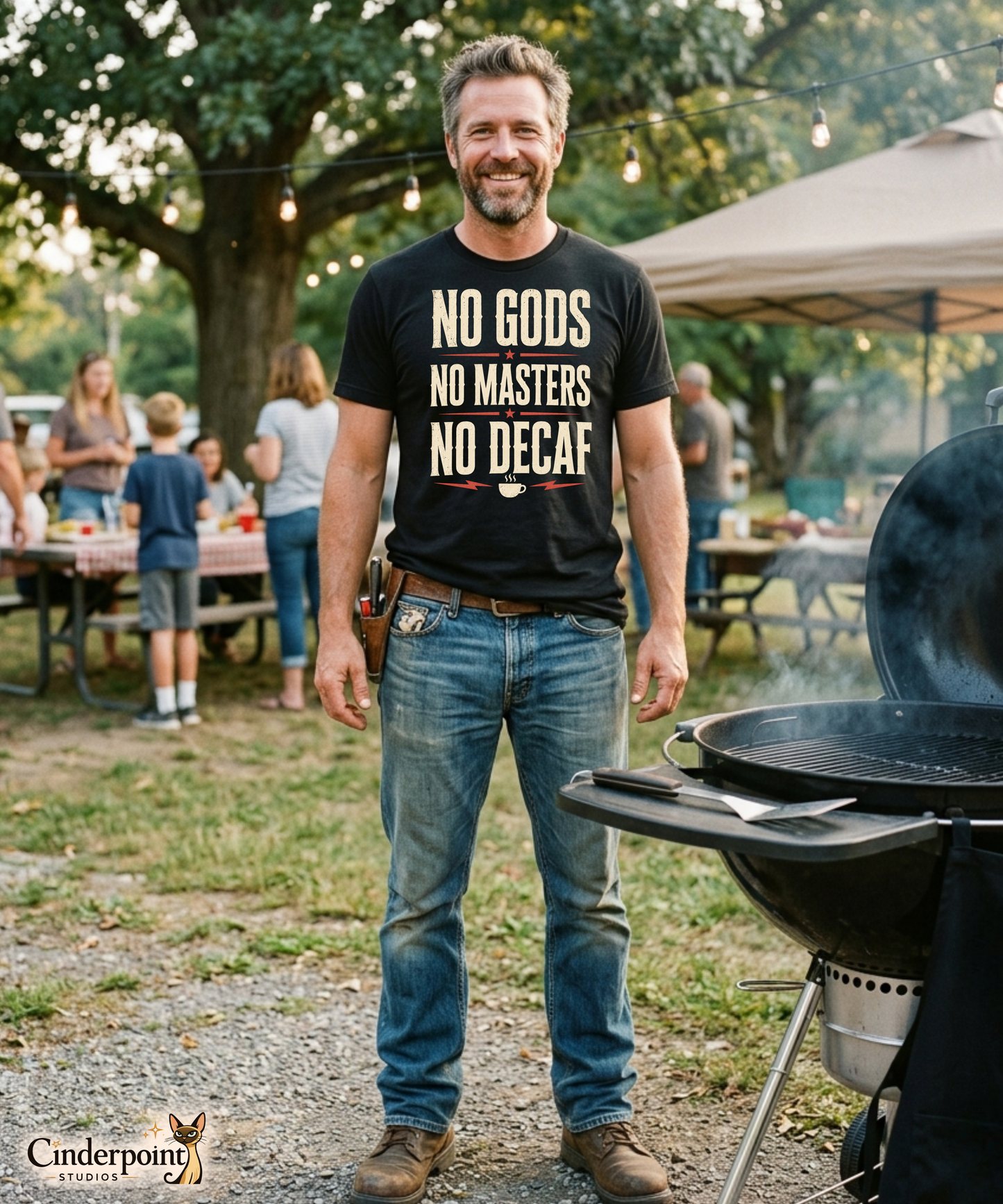 A man at a cookout wearing a black graphic tee with the No Gods No Masters No Decaf artwork by Cinderpoint Studios, styled as a boutique retro coffee humor shirt with bold slogan typography and red accent details.