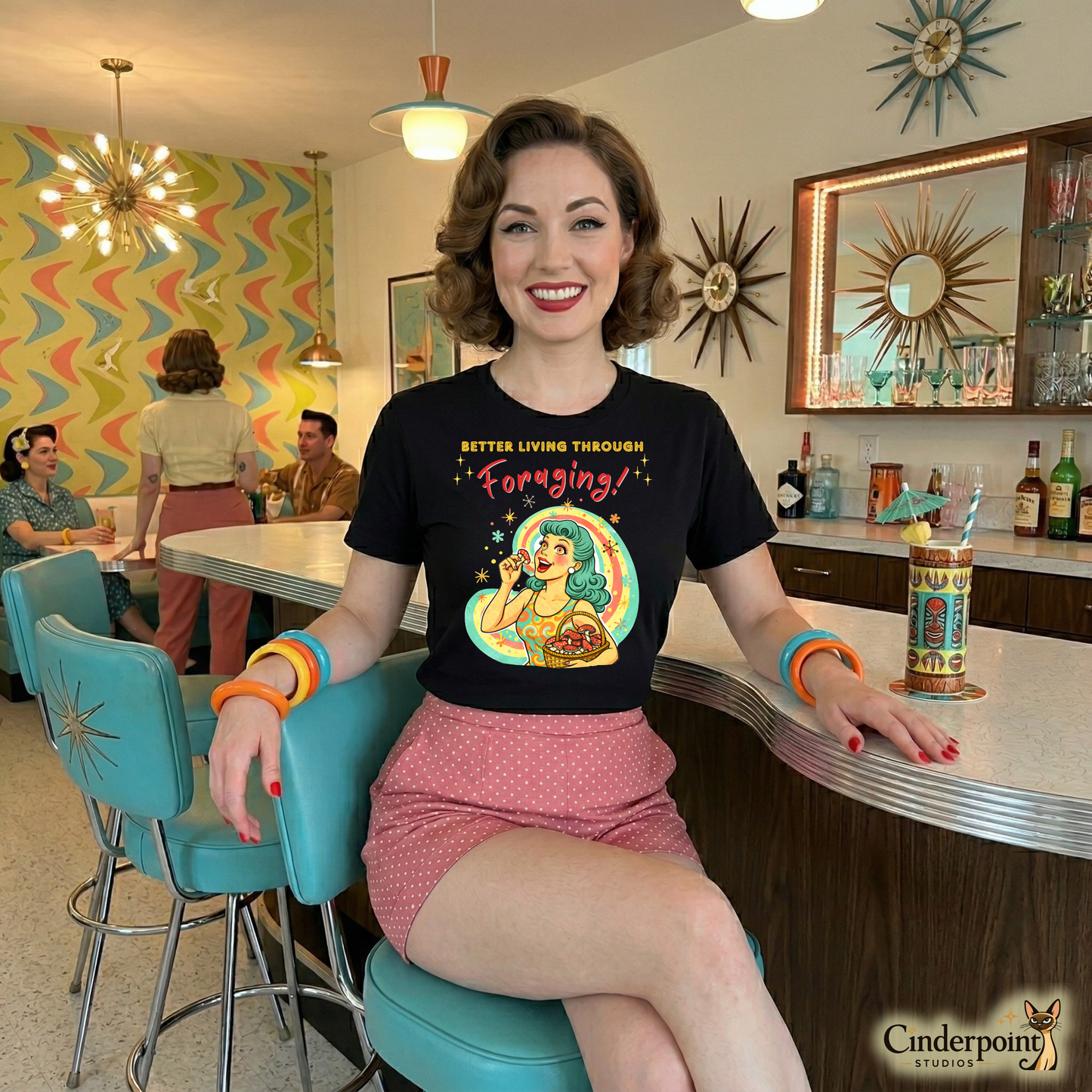 A woman sitting in a retro diner wearing a graphic tee. T-shirt shows a Retro watercolor illustration of a woman with teal hair and wide eyes holding a basket of red mushrooms on a black t-shirt.