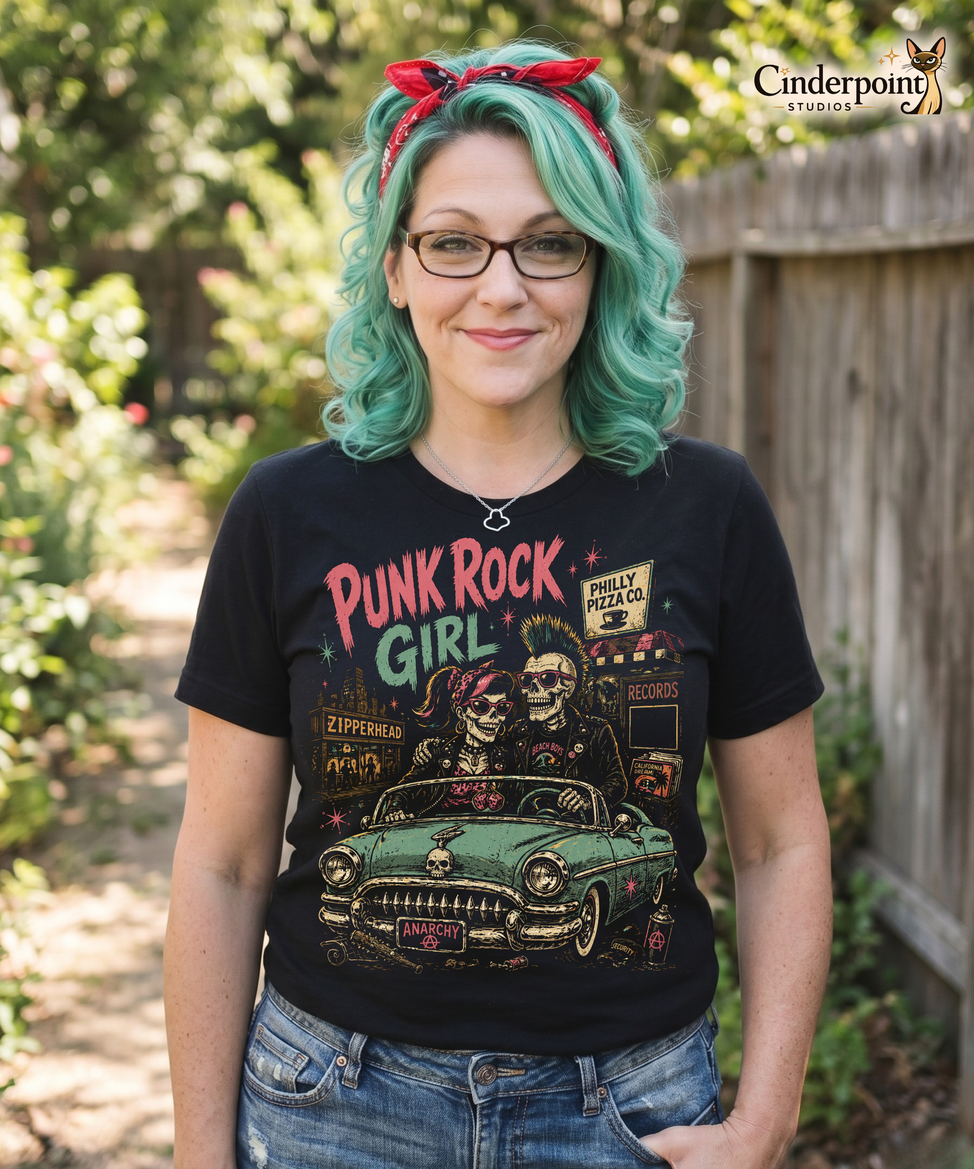 A retro-style graphic on a black t-shirt featuring two skeletons—a male with a mohawk and a female with a pink bow—driving a teal 1955 Chevy past iconic Philadelphia punk landmarks.