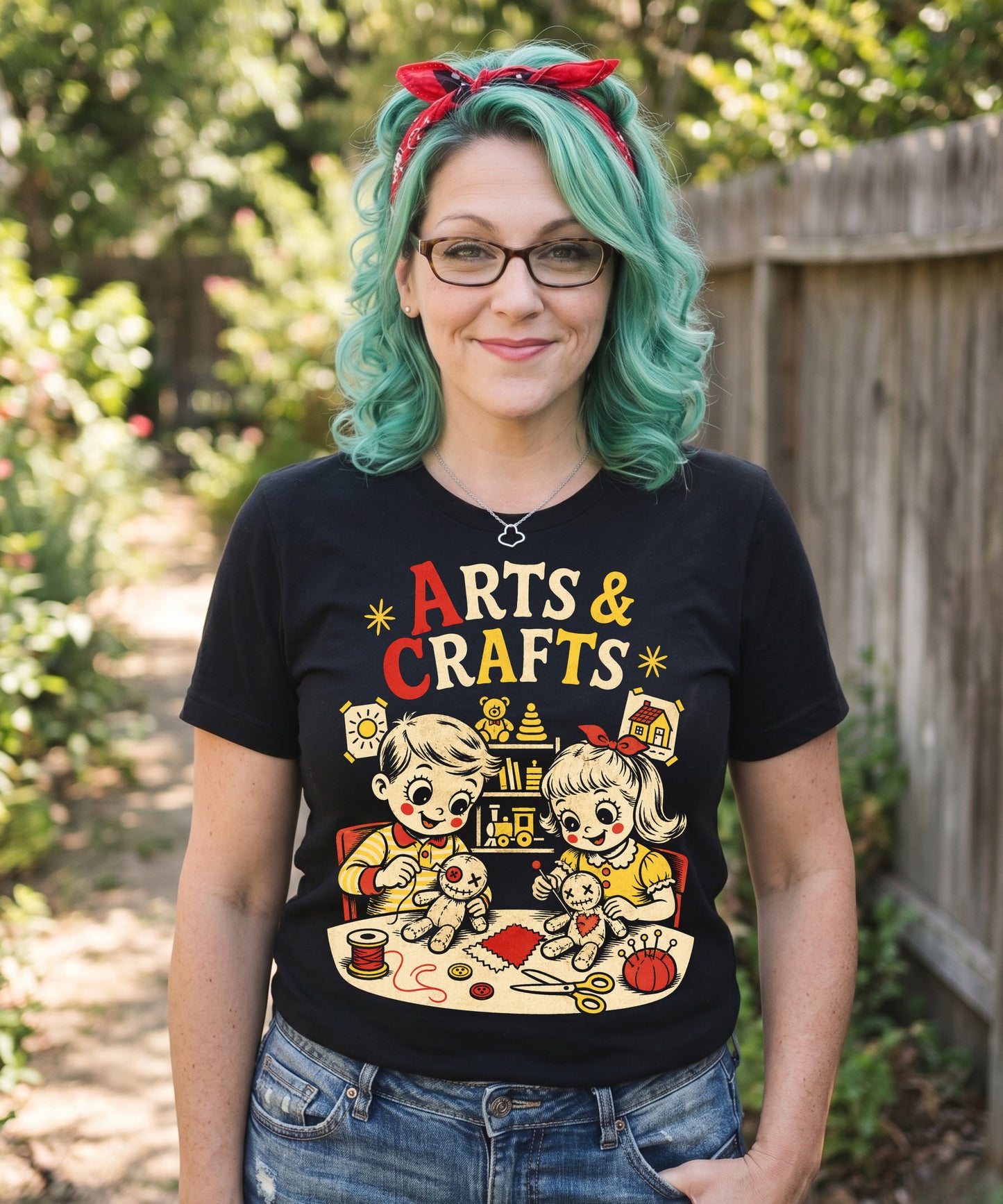 A retro-style graphic t-shirt featuring a creepy-cute voodoo doll with "Arts & Crafts" in stylized, vintage-inspired lettering, perfect for dark humor and goth fans.