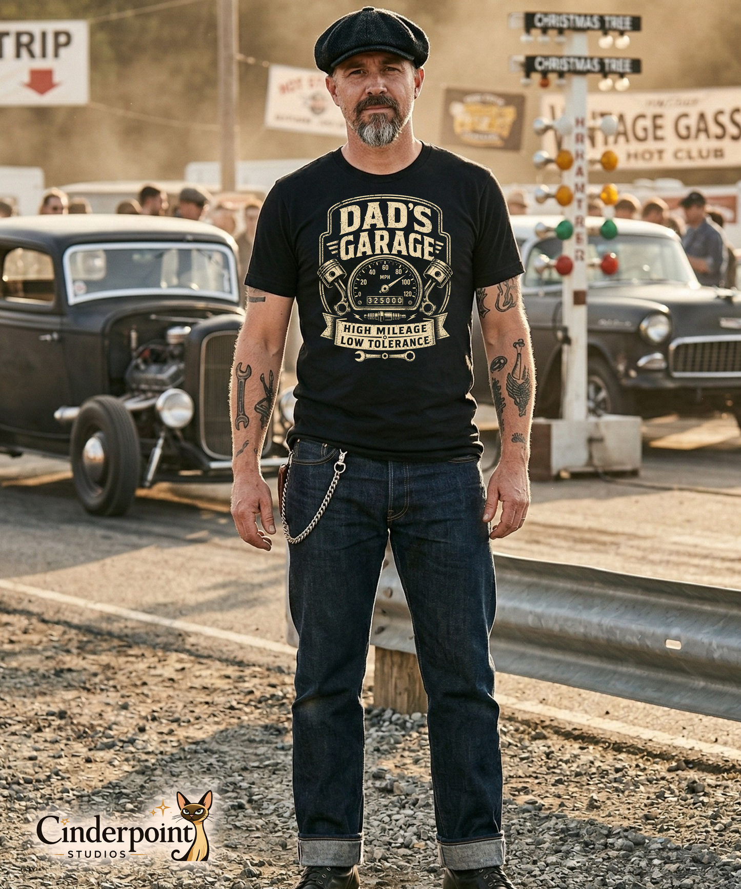 Man wearing a black graphic tee featuring original Cinderpoint Studios artwork for Dad’s Garage, a one-color retro garage badge design with bold lettering, a speedometer, pistons, spark plug, wrench, and High Mileage Low Tolerance text.