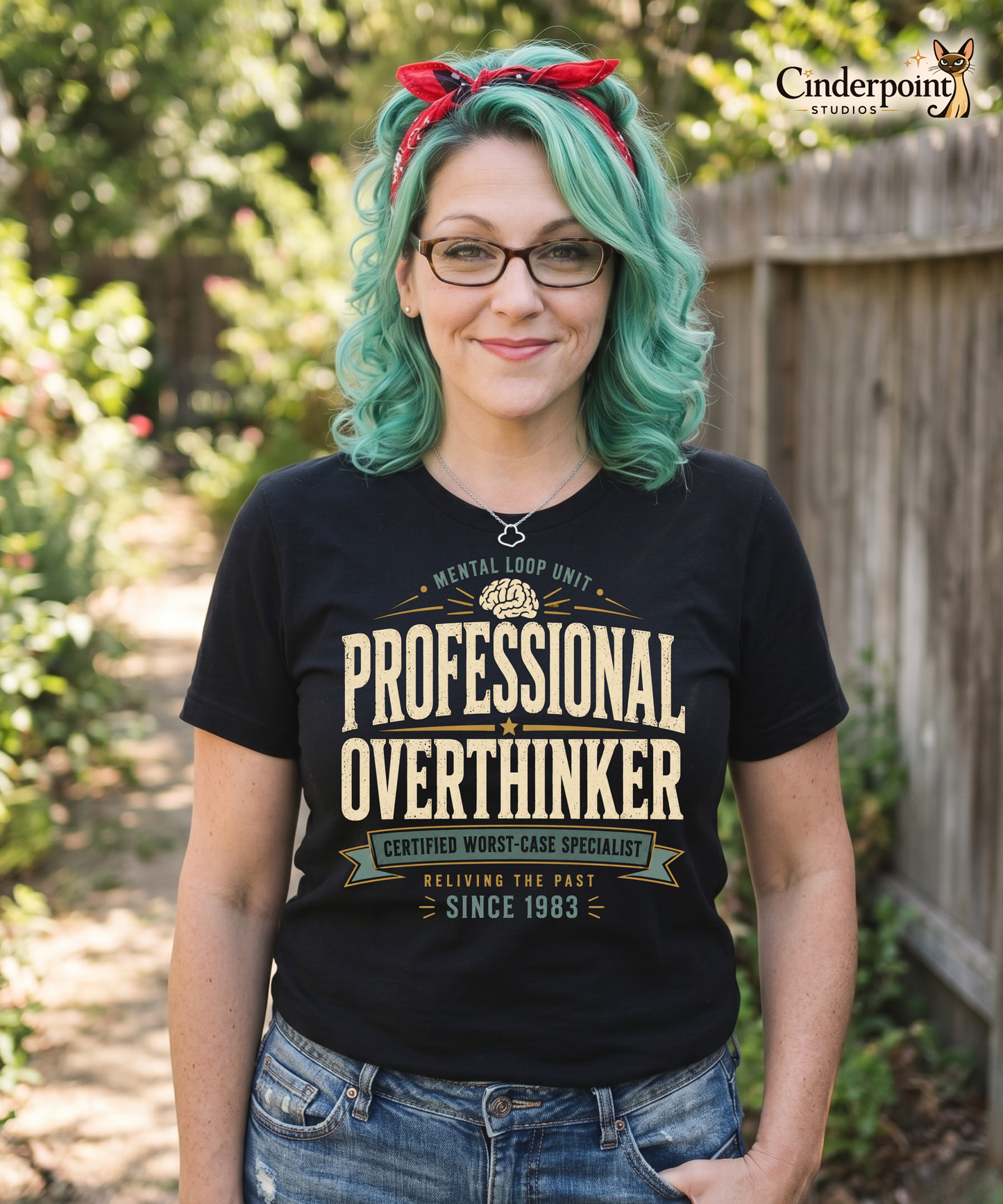 Auntie mel wearing a black graphic tee with the Professional Overthinker design by Cinderpoint Studios, featuring retro badge-style lettering, a brain graphic, and Mental Loop Unit text.