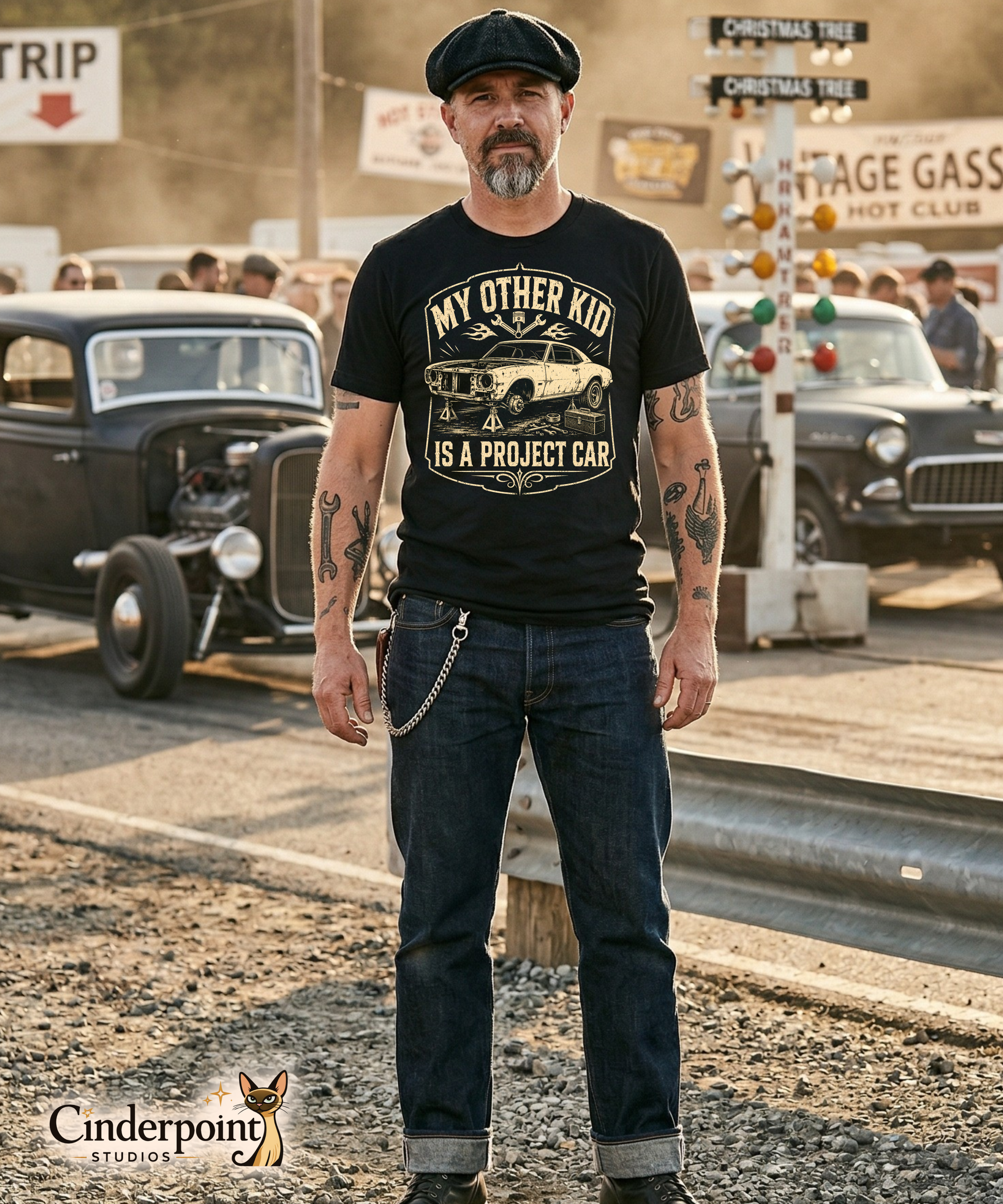 Man wearing a black graphic tee featuring original Cinderpoint Studios artwork for My Other Kid Is a Project Car, a one-color retro garage design with a classic project car on jack stands, tools, piston and wrench accents, flames, and bold vintage lettering.