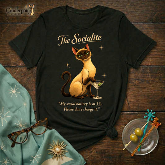 The Socialite Book of Lyle t-shirt design featuring Lyle, a sleek Siamese cat beside a martini glass with the quote “My social battery is at 1%. Please don’t charge it.”