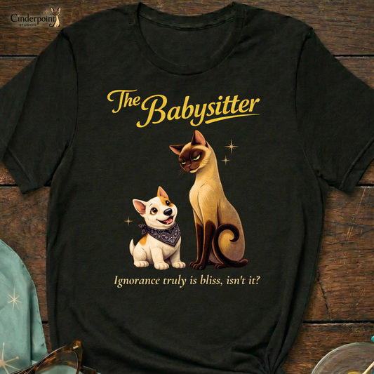 A black Bella+Canvas 3001 t-shirt featuring "The Babysitter" design on a dark wood grain table. The design shows a judgmental Siamese cat looking down at a happy Bull Terrier puppy with the text "The Babysitter" and "Ignorance truly is bliss, isn't it?" Accessories include vintage glasses and a starburst scarf.