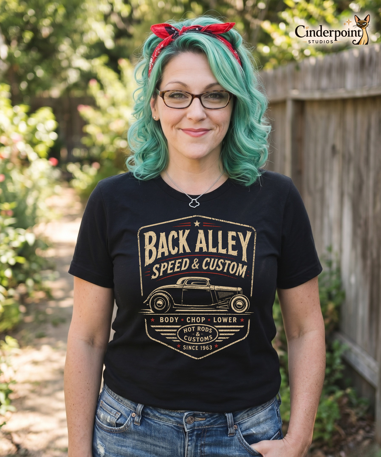 Woman with retro styled aqua hair is wearing a a black graphic tee featuring original Cinderpoint Studios artwork for Back Alley Speed & Custom, a retro hot rod garage design with a chopped custom car profile, bold distressed lettering, red accent details, Body Chop Lower text, and Hot Rods & Customs badge.