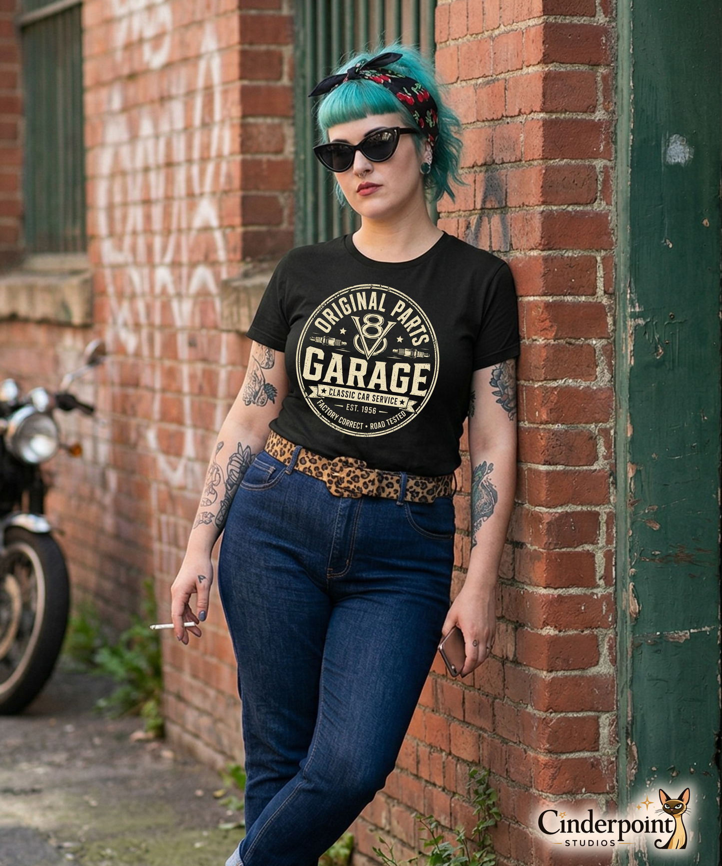 A punk rock girl wearing a a black graphic tee featuring original Cinderpoint Studios artwork for Original Parts Garage, a one-color classic car service badge design with bold lettering, V8 emblem, spark plugs, Classic Car Service banner, Factory Correct text, and Road Tested details.