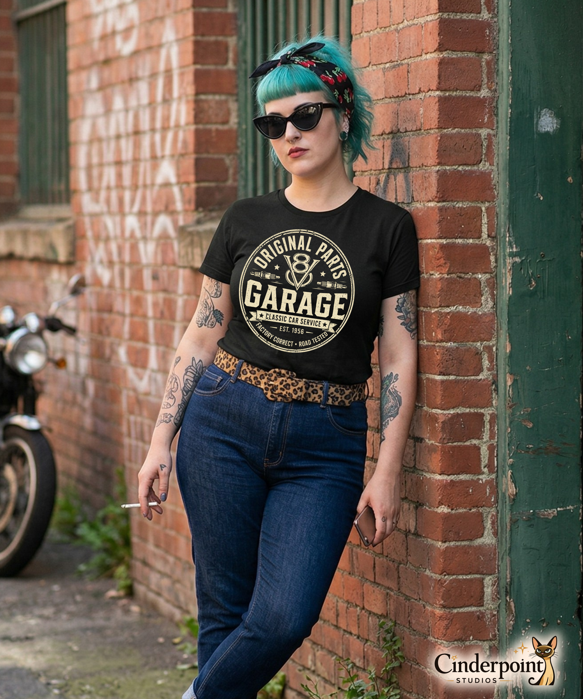 A punk rock girl wearing a a black graphic tee featuring original Cinderpoint Studios artwork for Original Parts Garage, a one-color classic car service badge design with bold lettering, V8 emblem, spark plugs, Classic Car Service banner, Factory Correct text, and Road Tested details.