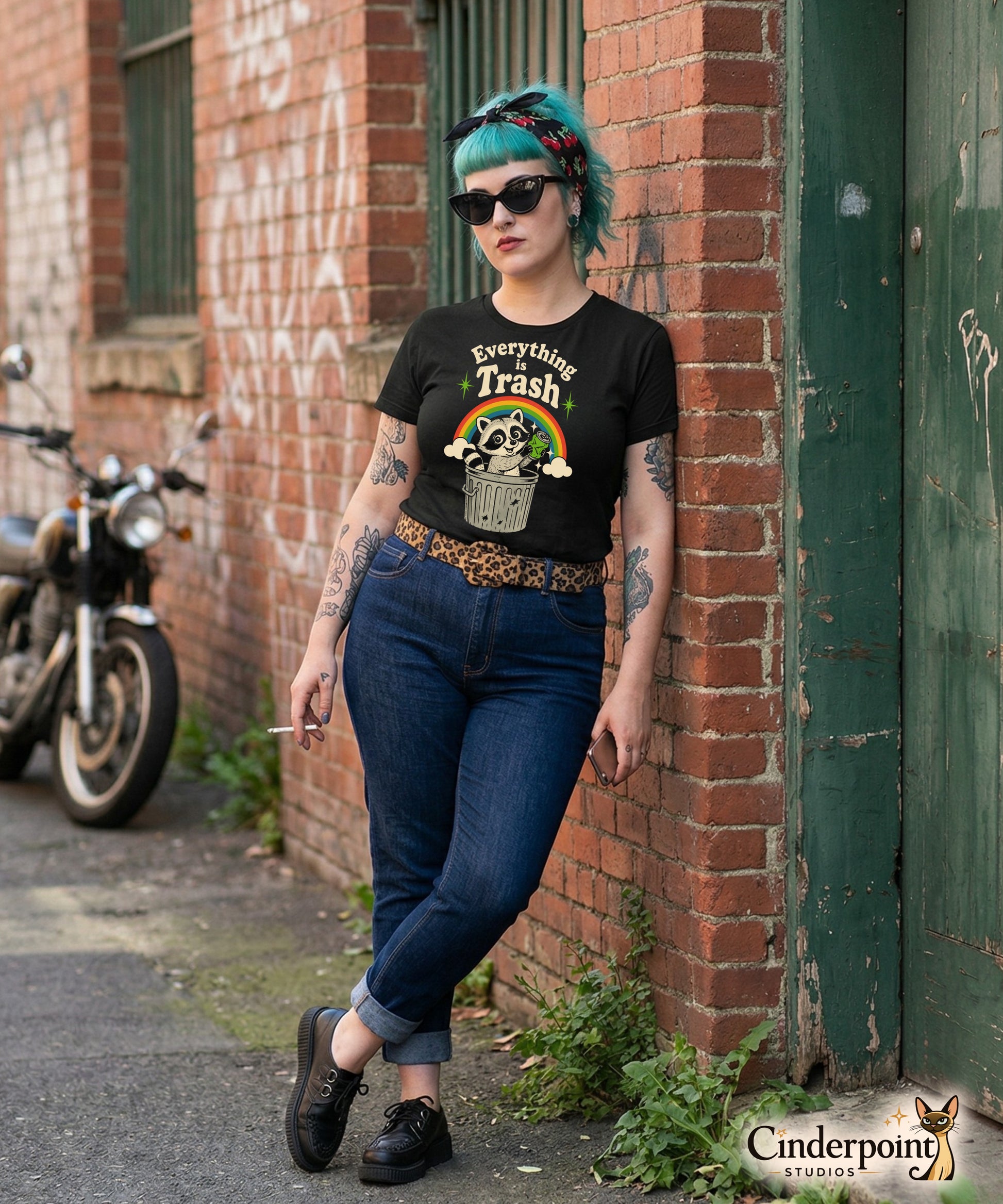 A retro 1970s-style graphic t-shirt featuring a cute raccoon sitting under a vibrant rainbow with the text "Everything Is Trash" in vintage-inspired lettering