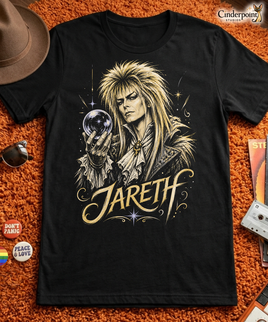 A gritty, high-contrast artistic portrait of Jareth the Goblin King on a black t-shirt, featuring his iconic 80s glam hair and a crystal ball with a starburst.