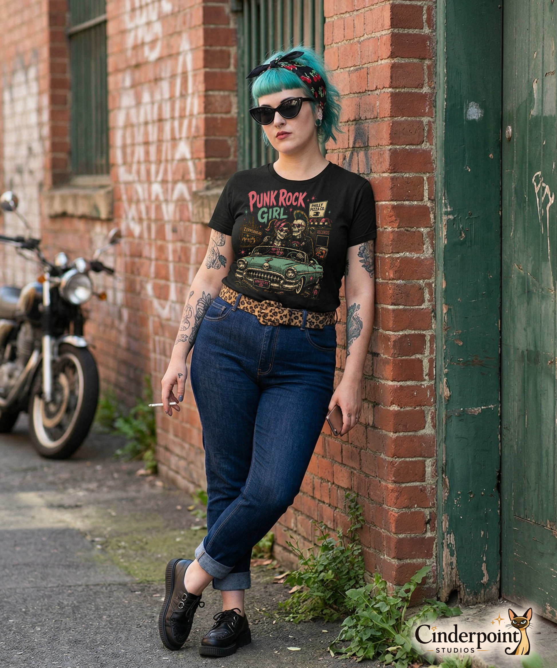 A retro-style graphic on a black t-shirt featuring two skeletons—a male with a mohawk and a female with a pink bow—driving a teal 1955 Chevy past iconic Philadelphia punk landmarks.