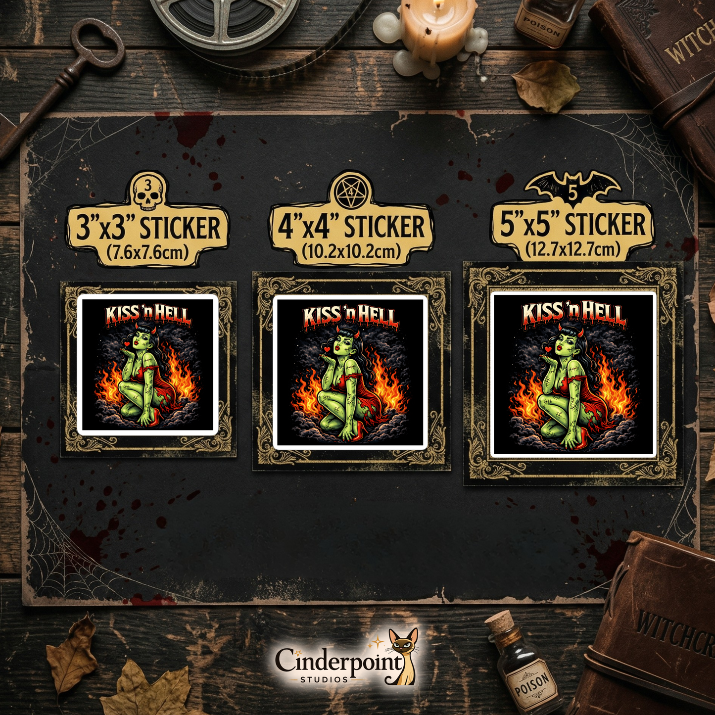 A dark wood tabletop featuring three "Kiss 'n Hell" stickers in 3-inch, 4-inch, and 5-inch sizes. Styled with a "Witchcraft" grimoire, poison bottles, a candle, and a brass skeleton key.