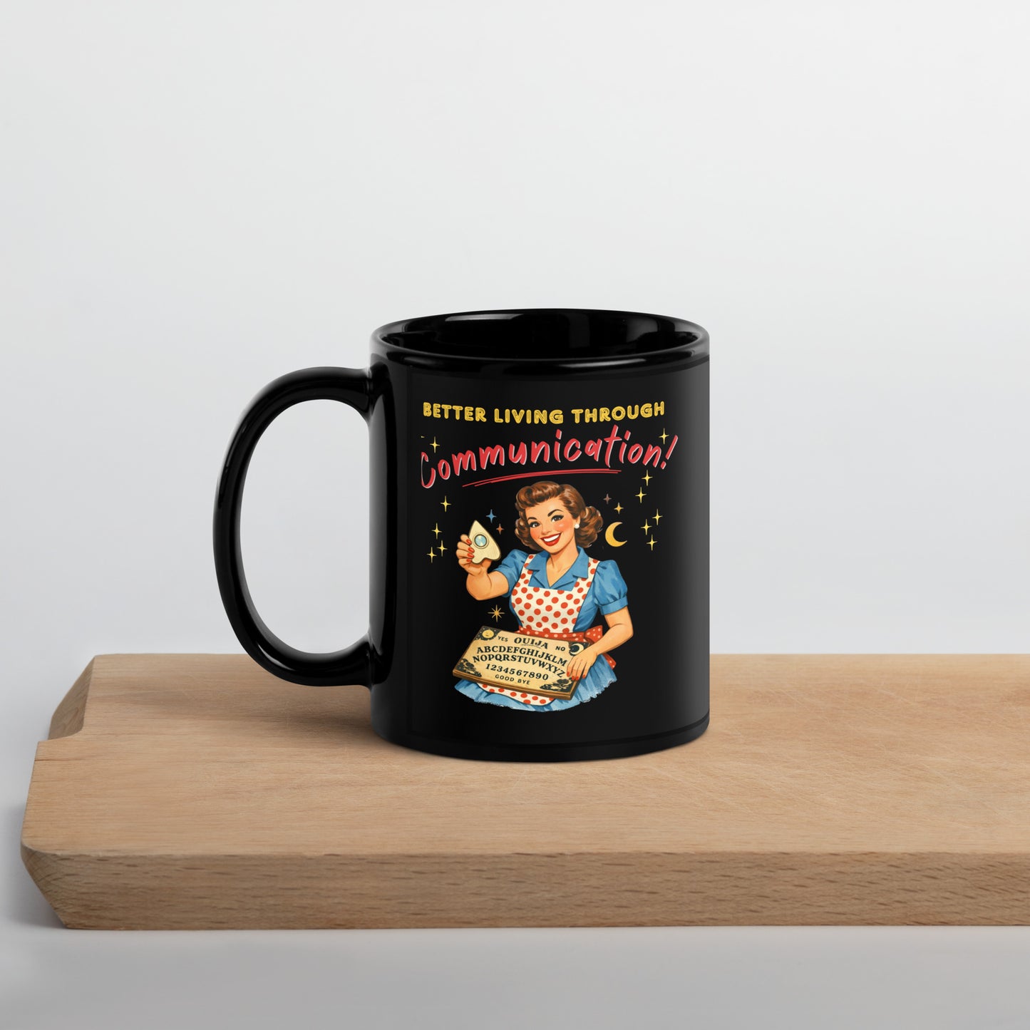 Better Living Through Communication black ceramic mug — vintage 1950s retro housewife in polka dot apron holding ouija board and planchette, printed on both sides by Cinderpoint Studios