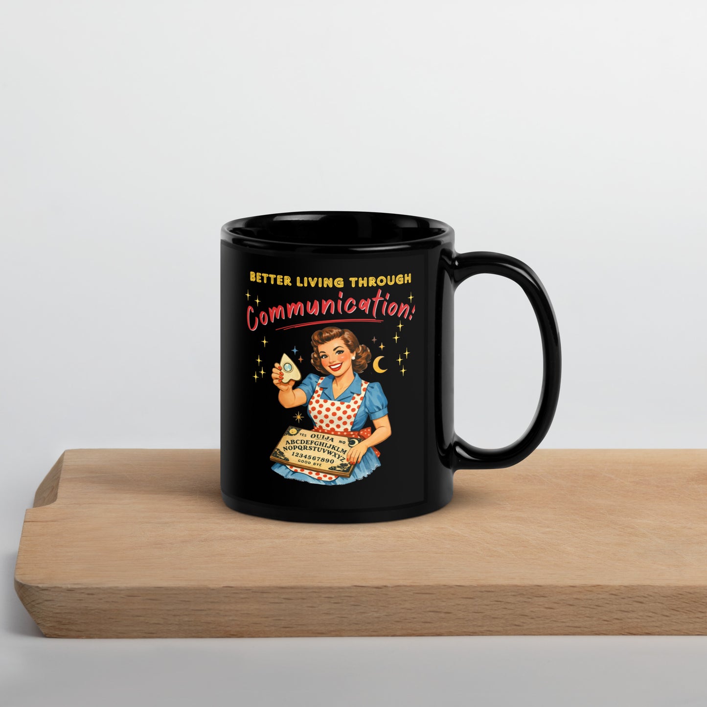Better Living Through Communication black ceramic mug — vintage 1950s retro housewife in polka dot apron holding ouija board and planchette, printed on both sides by Cinderpoint Studios