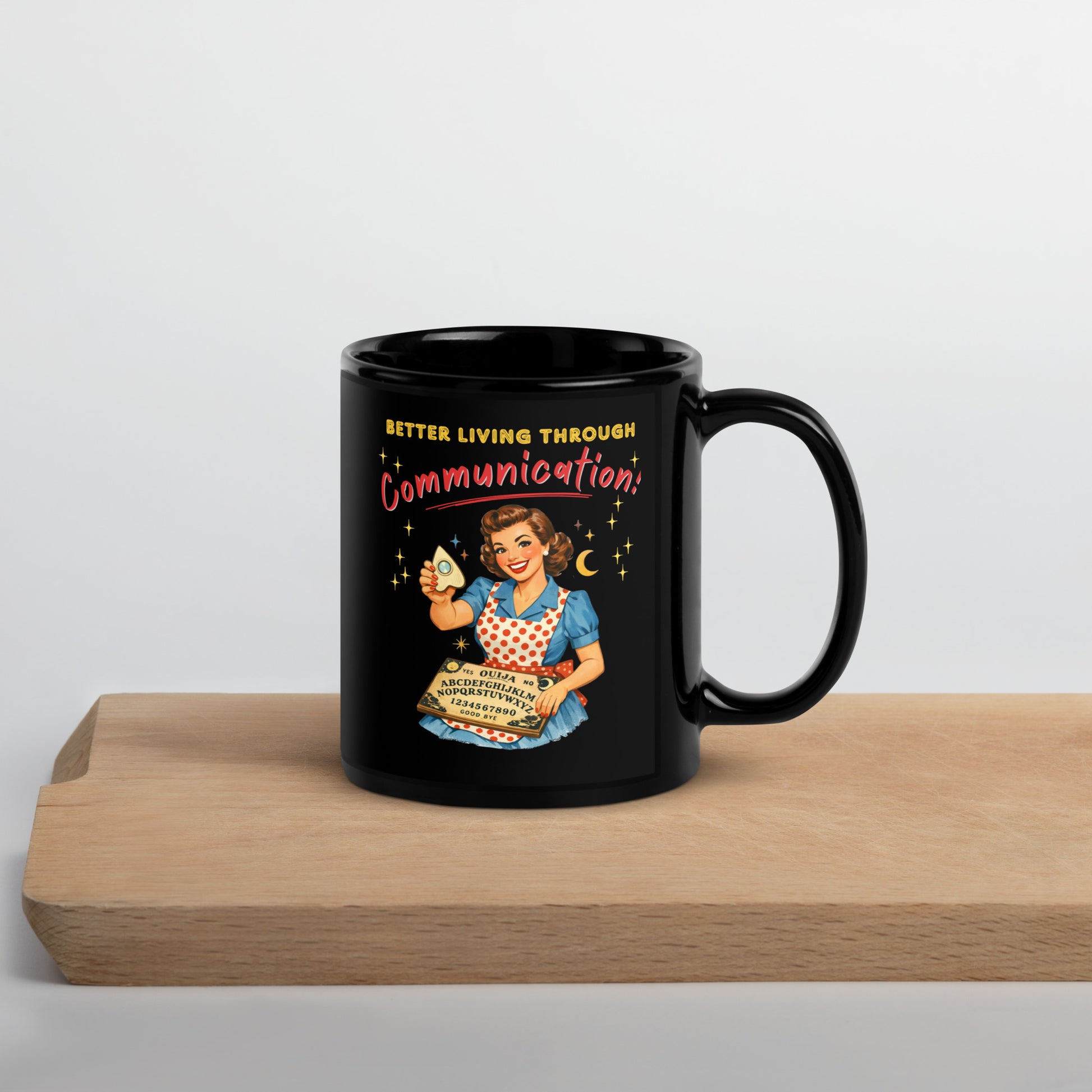 Better Living Through Communication black ceramic mug — vintage 1950s retro housewife in polka dot apron holding ouija board and planchette, printed on both sides by Cinderpoint Studios