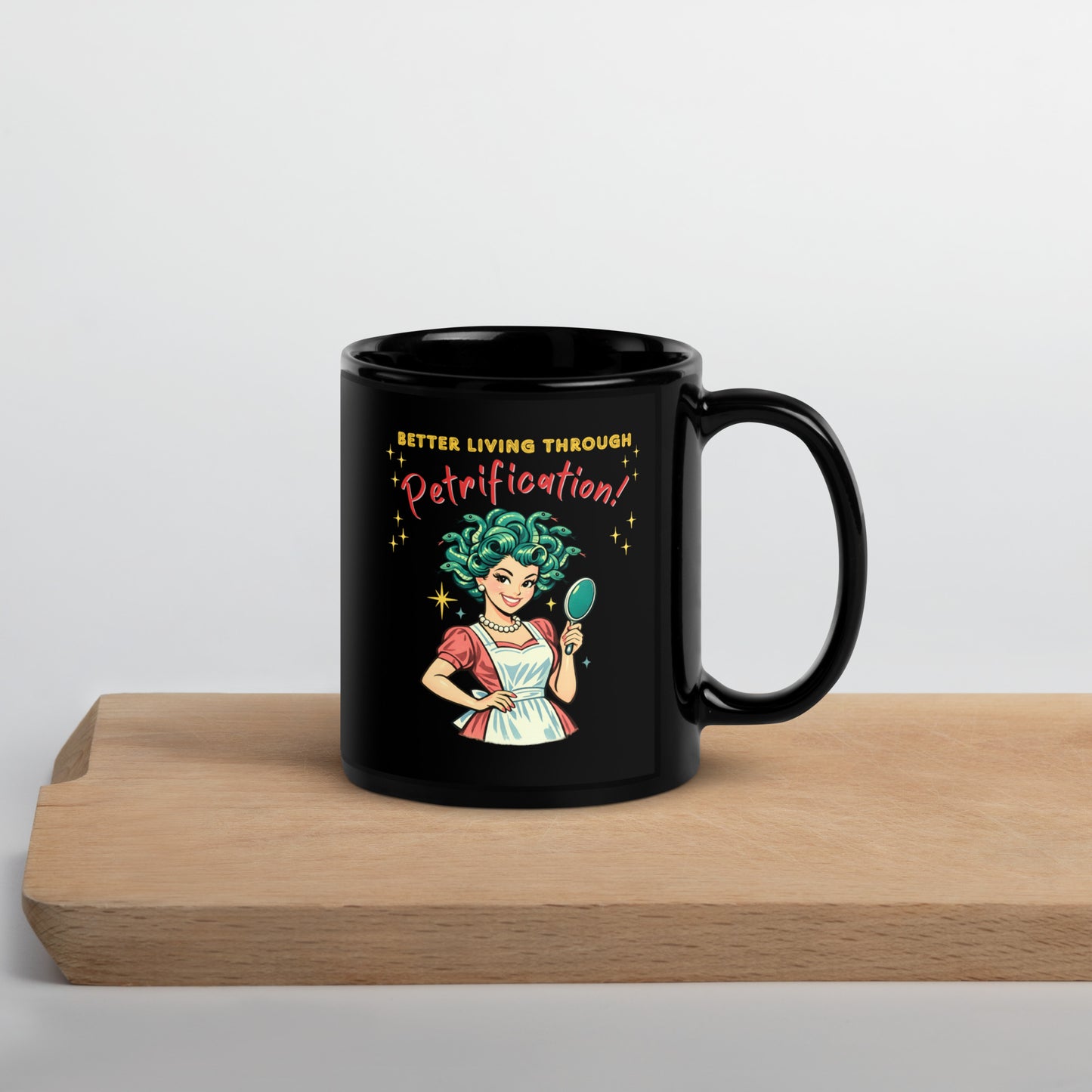 Better Living Through Petrification black ceramic mug — vintage 1950s retro Medusa housewife with styled snake hair holding a hand mirror and smiling confidently in pearls and apron, printed on both sides by Cinderpoint Studios