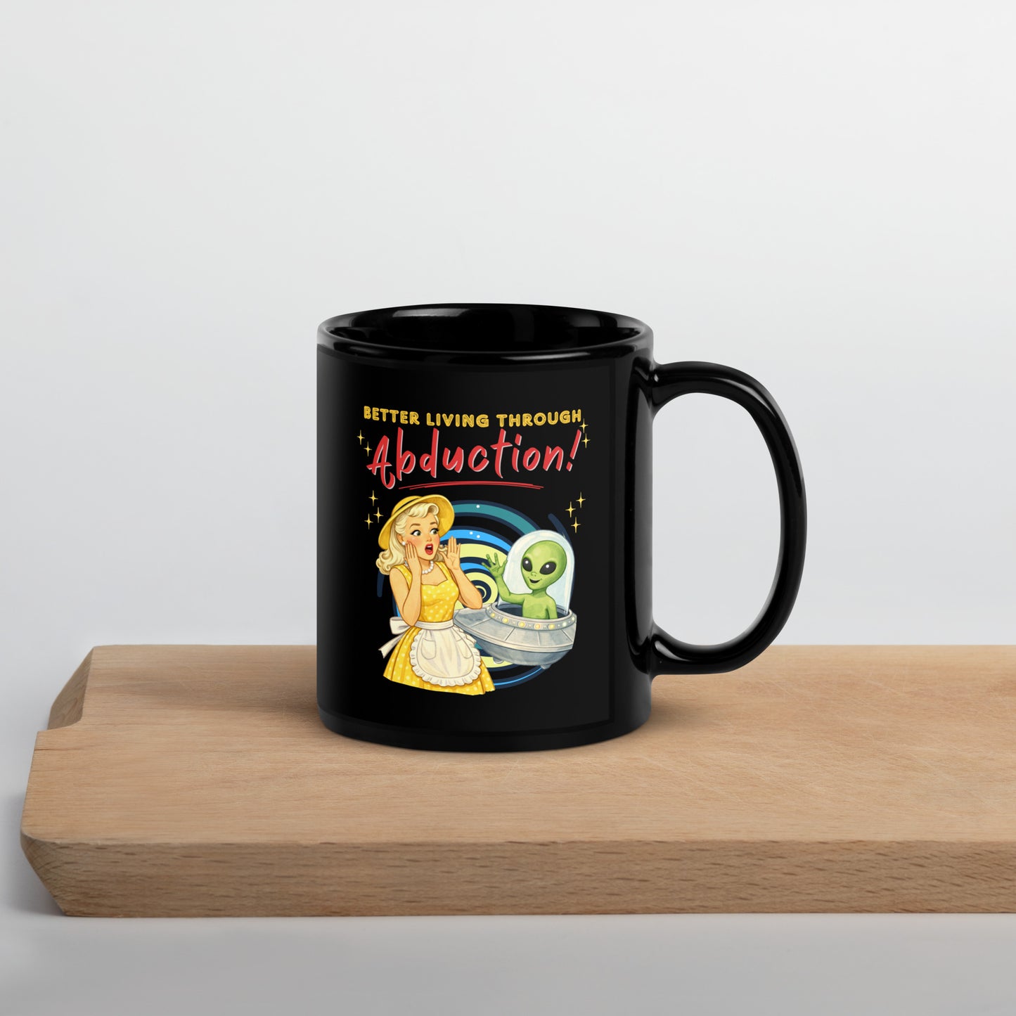 Better Living Through Abduction black ceramic mug — vintage 1950s retro blonde housewife in yellow polka dot dress reacting with delight to a friendly green alien waving from a silver saucer, printed on both sides by Cinderpoint Studios