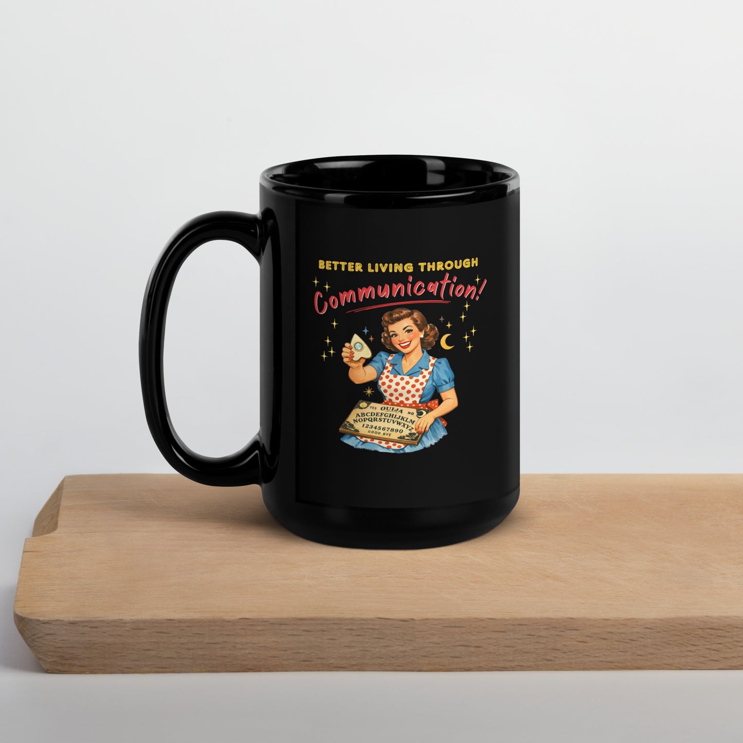 Better Living Through Communication black ceramic mug — vintage 1950s retro housewife in polka dot apron holding ouija board and planchette, printed on both sides by Cinderpoint Studios