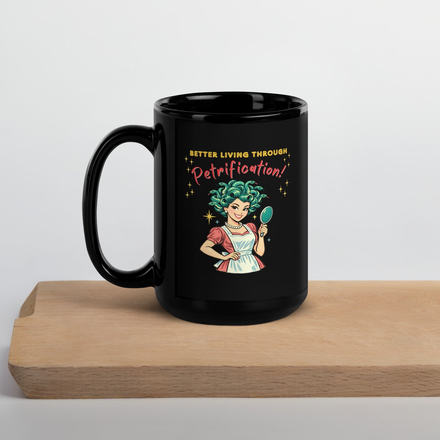 Better Living Through Petrification black ceramic mug — vintage 1950s retro Medusa housewife with styled snake hair holding a hand mirror and smiling confidently in pearls and apron, printed on both sides by Cinderpoint Studios