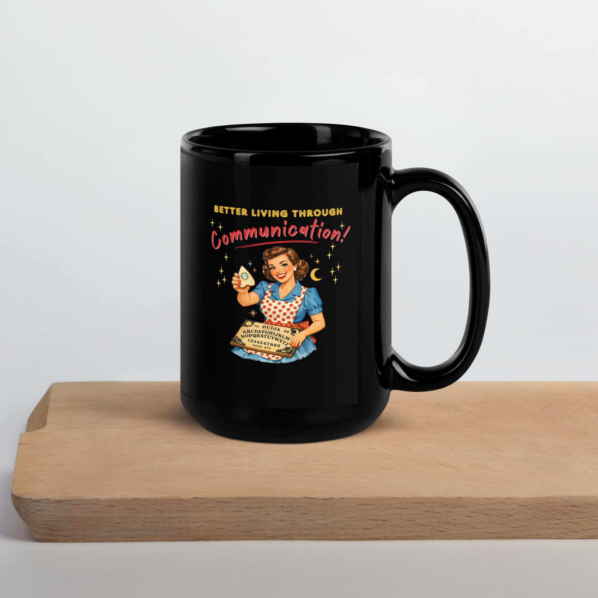 Better Living Through Communication black ceramic mug — vintage 1950s retro housewife in polka dot apron holding ouija board and planchette, printed on both sides by Cinderpoint Studios