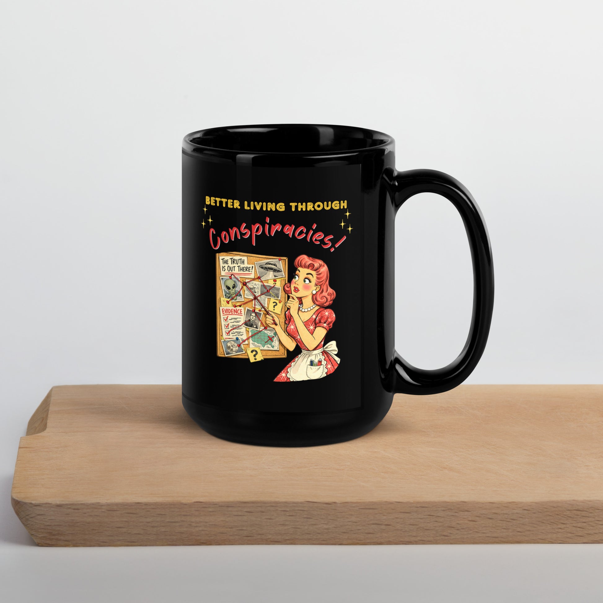 Better Living Through Conspiracies black ceramic mug — vintage 1950s retro housewife pointing at alien evidence cork board with red string and UFO photos, printed on both sides by Cinderpoint Studios