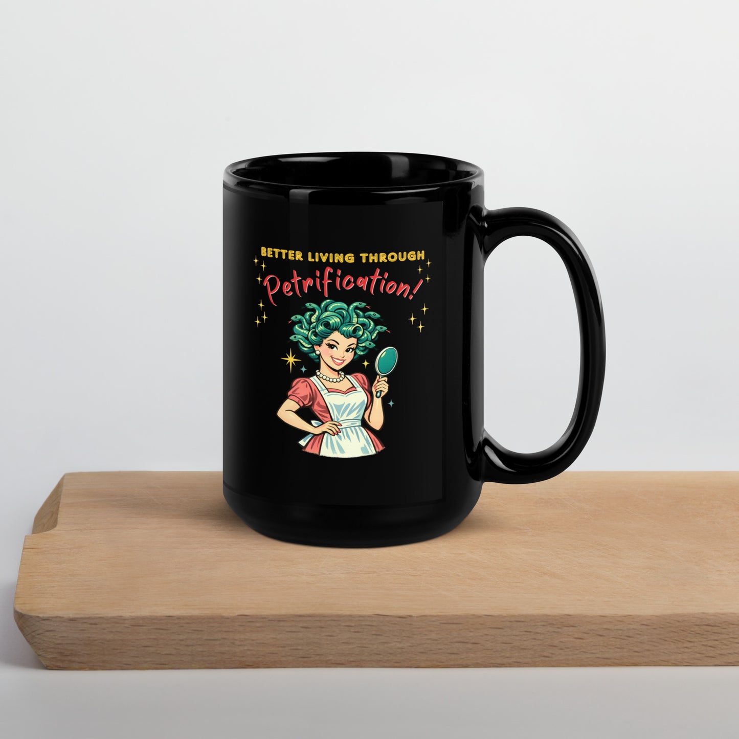 Better Living Through Petrification black ceramic mug — vintage 1950s retro Medusa housewife with styled snake hair holding a hand mirror and smiling confidently in pearls and apron, printed on both sides by Cinderpoint Studios